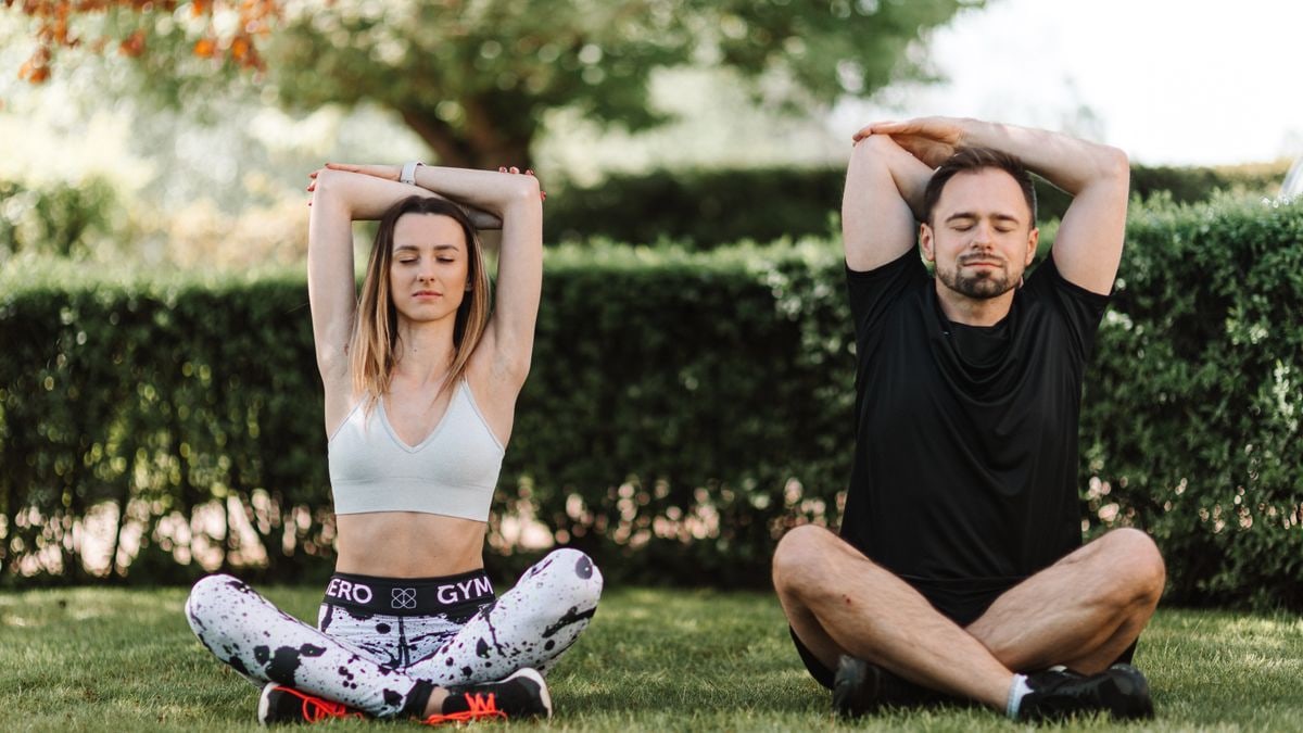 A couple practicing yoga and meditation in a serene outdoor setting, enhancing well-being.